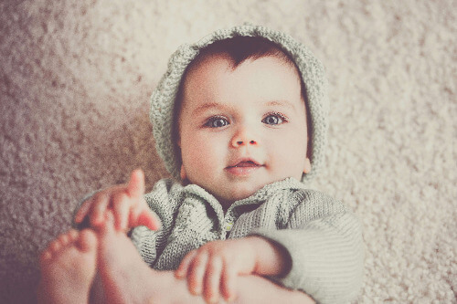 Baby boy holding feet.