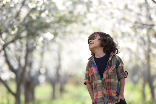 Boy with sun on his face and hands in pockets