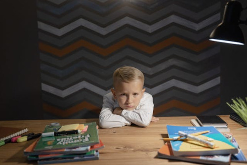 Boy with head in arms which are on the table. 