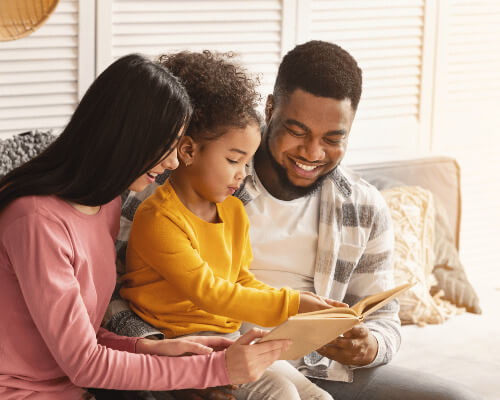 Parents reading book to child. 