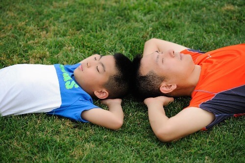 dad an son on grass looking up at sky.