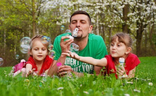 Dad blowing bubbles with kids.