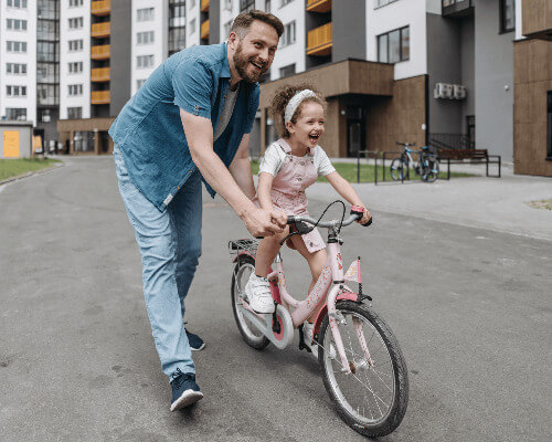 Dad teaching girl to ride bike. 