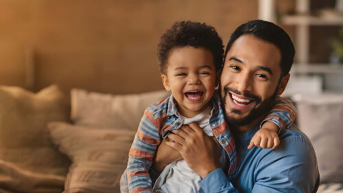 Dad holding son and they are laughing together.