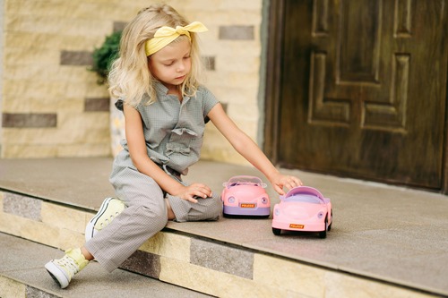 Gentle parenting for introverted kids, preschool girl playing with cars on steps