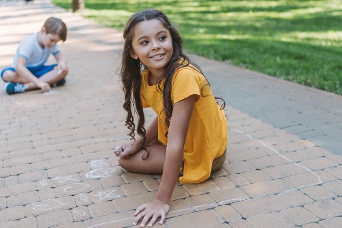 Girl sitting on sidewalk.