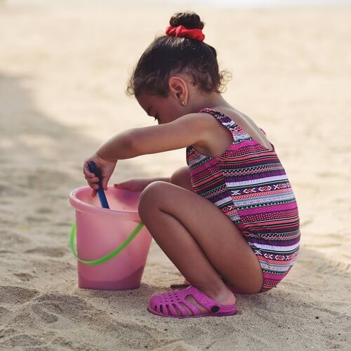 Girl playing in sand on beach. 