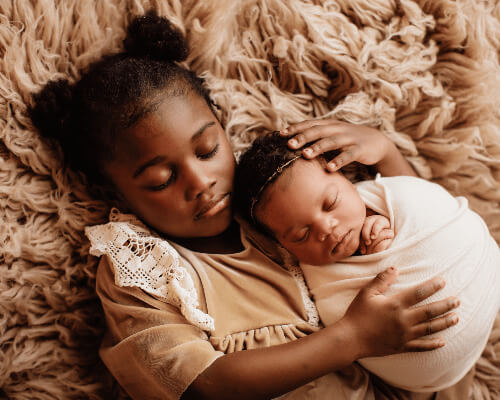 Girl sleeping with baby sister.