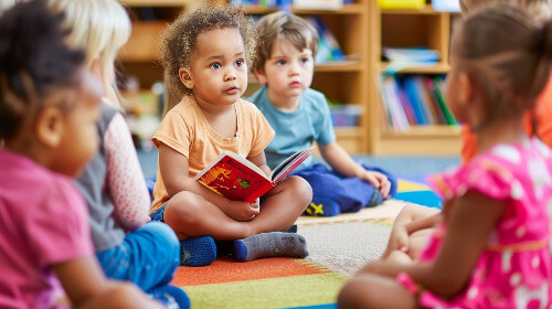 Little girl reading to class.