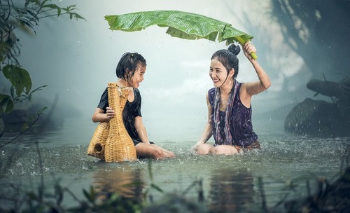 Mom and daughter in pond while it is raining. 