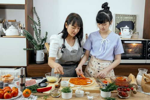 Mom and daughter making pizza.