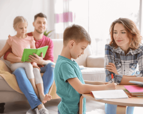 Mom helping boy with homework, dad has daughter on his knee.