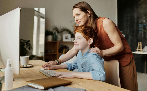 Mom helping son on computer.