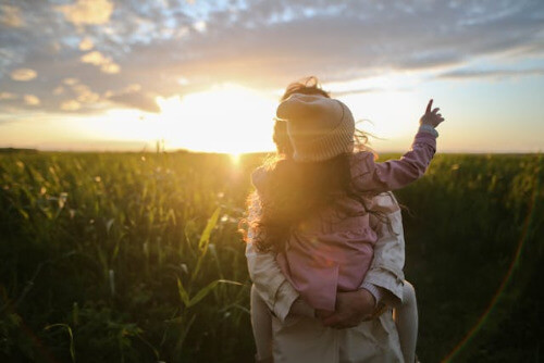 Mom holding child during sun set.