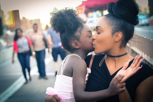 Mom kissing daughter on cheek.