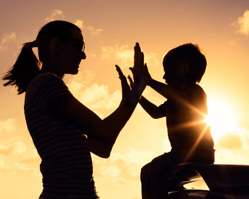 Mom an child playing in the sunset.