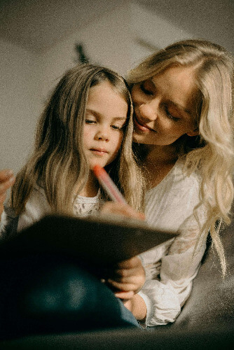 Mom watching child draw.