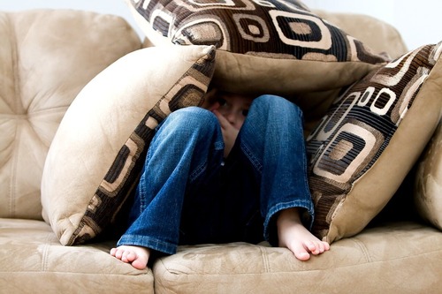 Raising an emotionally intense child, child on couch with pillows covering them. 