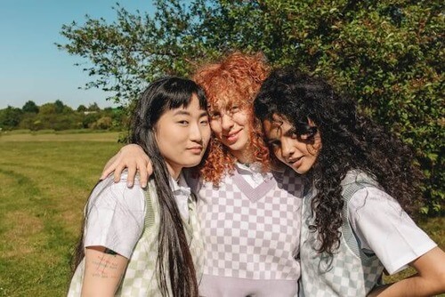 Three tween girls with arms on shoulders