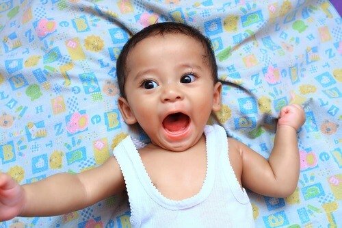 baby lying on blanket with mouth open