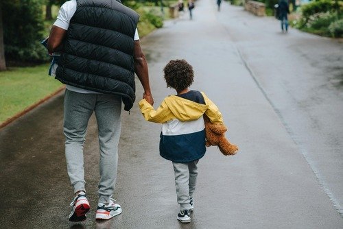 Dad walking with son nd holding his hand.