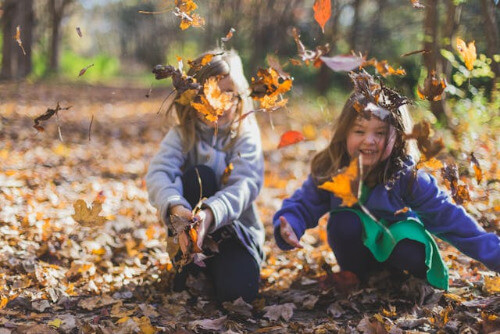 Girls having a wonderful time  playing in leaves.