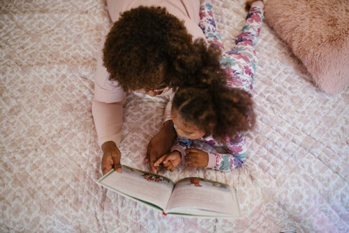 little girl and mom on bed reading