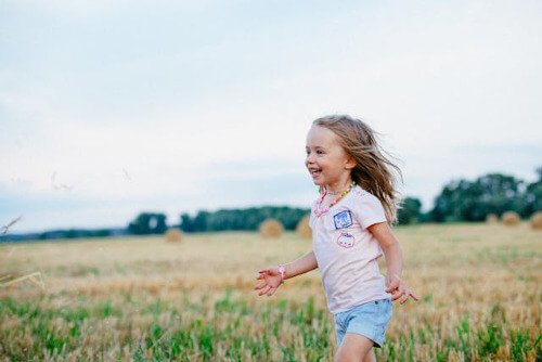 Little girl happily running in field.