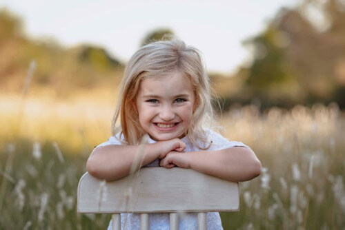 Girl facing backward on chair, smiling. 