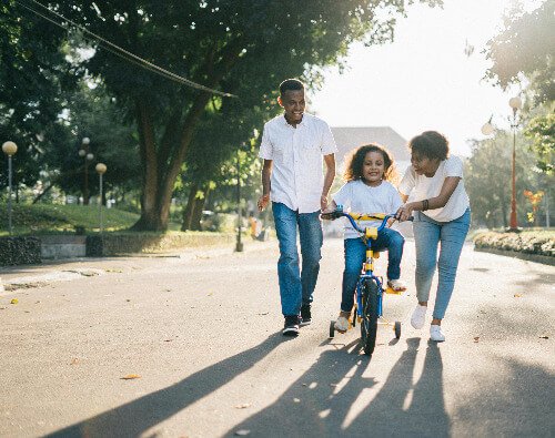 Parents teaching child to ride bike.