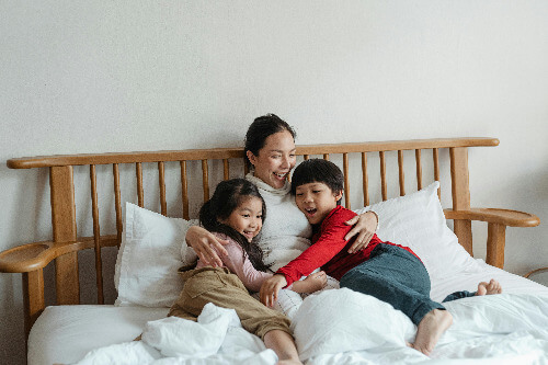 Mom and holding kids while sitting on bed