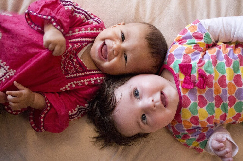 Baby girls lying with heads together.