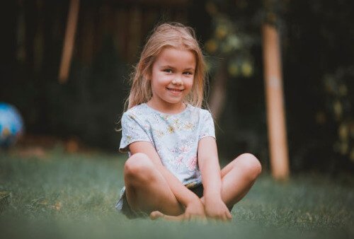 Young girl sitting on the grass and smiling. 